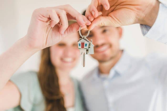 Smiling couple holding a house-shaped keychain with a key